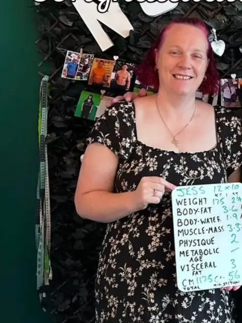 A woman holds up her whiteboard results in the club room